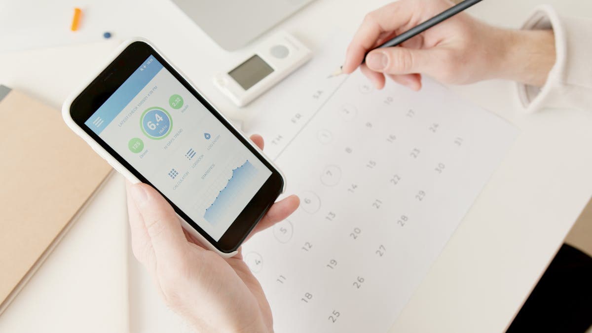 A smartphone displaying a medication tracking app with injection site history and dose log on a bedside table