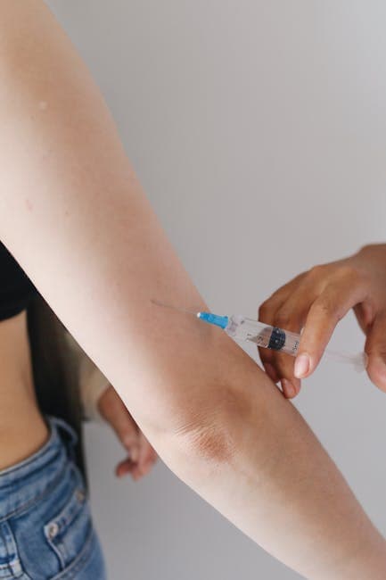 A man identifying an injection site on his outer thigh, with a syringe and alcohol swab in his other hand