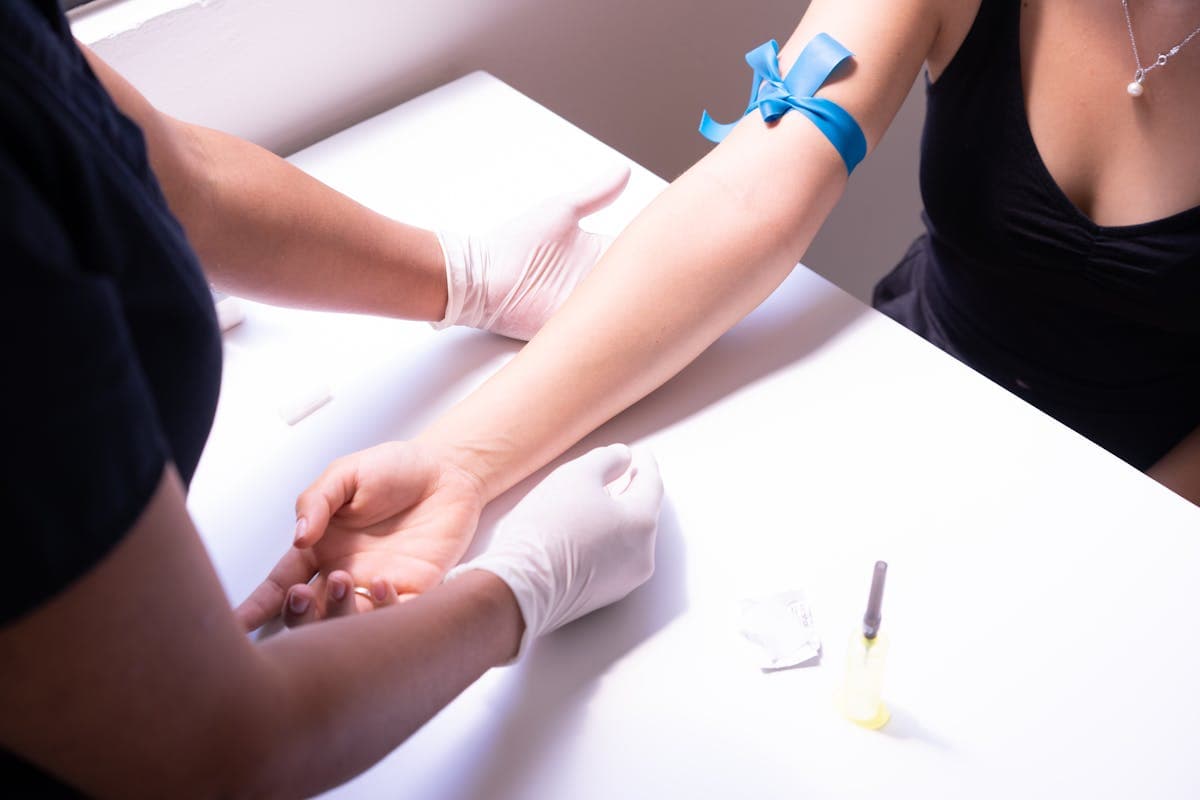 A patient sitting in a phlebotomy chair with a tourniquet on their arm, morning light coming through a clinic window
